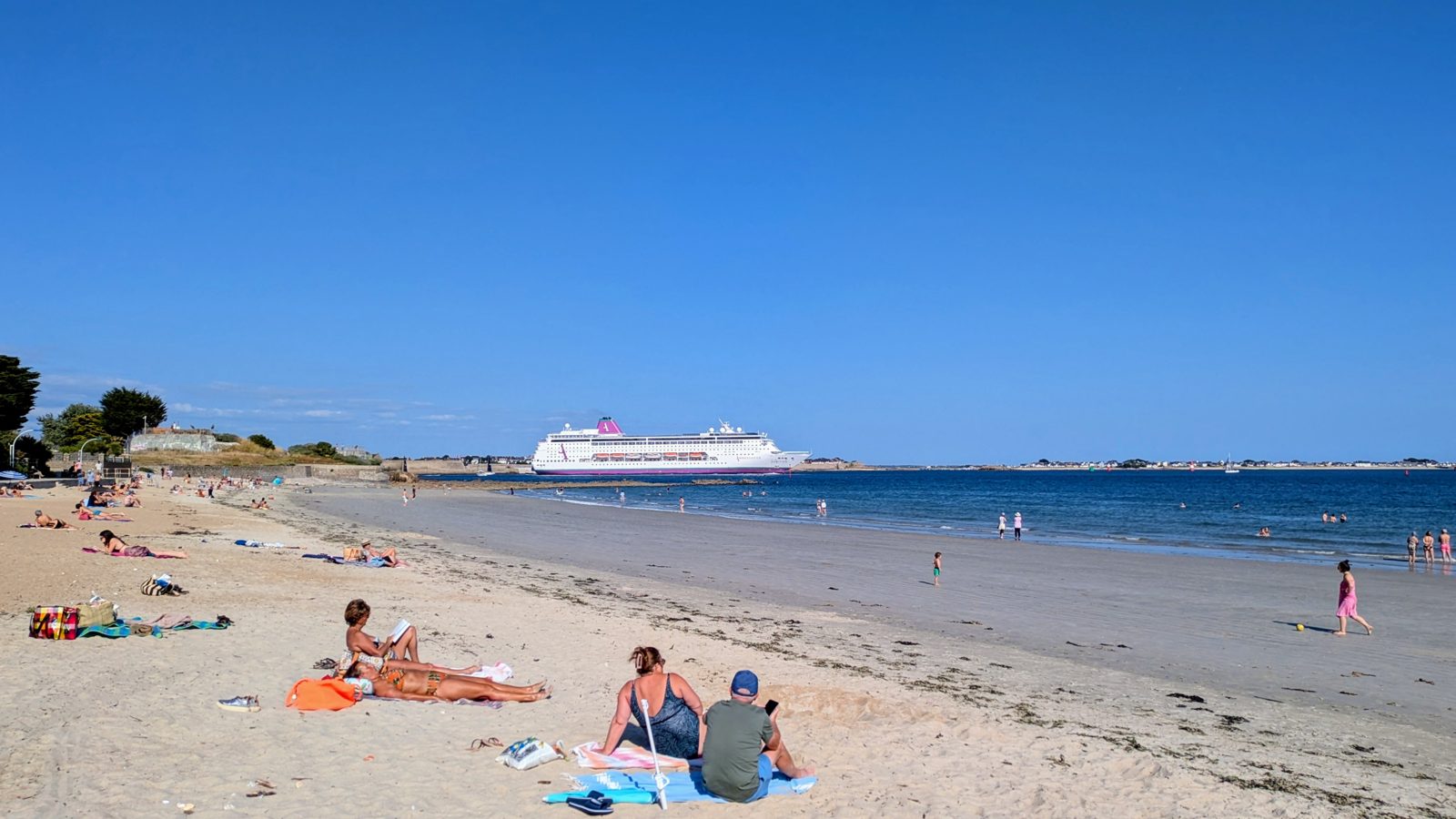La plage de Toulhars a Larmor-Plage, avec un paquebot entrant dans la rade de Lorient
